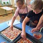 Uczniowie Łucja i Damian nakładają składniki na pizzę.jpg