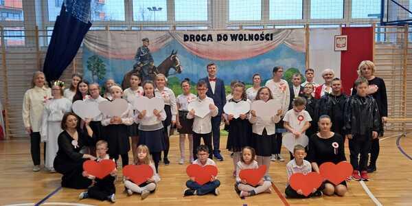 Uczniowie występujący podczas apelu z nauczycielami oraz panią Dyrektor Szkoły.jpg