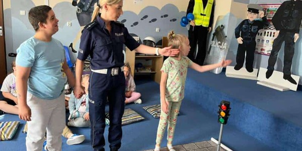 Uczniowie z panią policjantką uczą się prawidłowo przechodzić przez jezdnię.jpg
