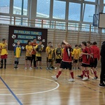 Uczestnicy XXI Turnieju Piłki Nożnej przygotowujący się do sportowych zmagań na sali gimnastycznej.jpg