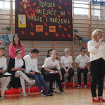 Prowadząca uroczystość szkolną przemawia do uczestników na sali gimnastycznej..jpg